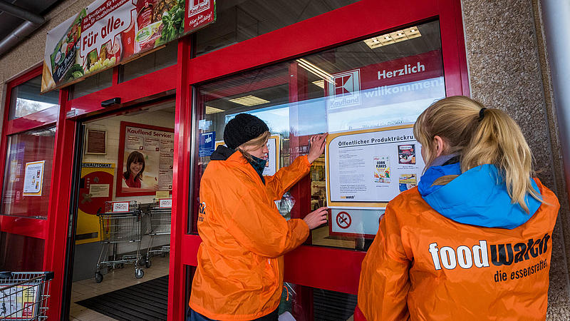 Aktivistinnen kleben Protestplakate an die Glastür einer Kauflandfiliale