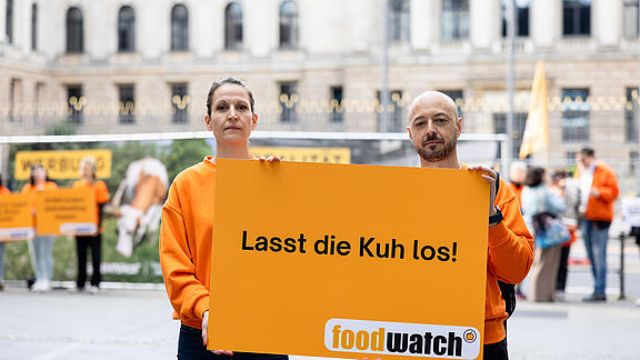 Zwei Aktivisten, die ein Schild mit der Forderung "Lasst die Kuh los" in die Kamera halten